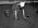 En städerska på 1970-talet, står på knä och skrubbar ett golv med en skurhink intill sig. Svartvit bild.