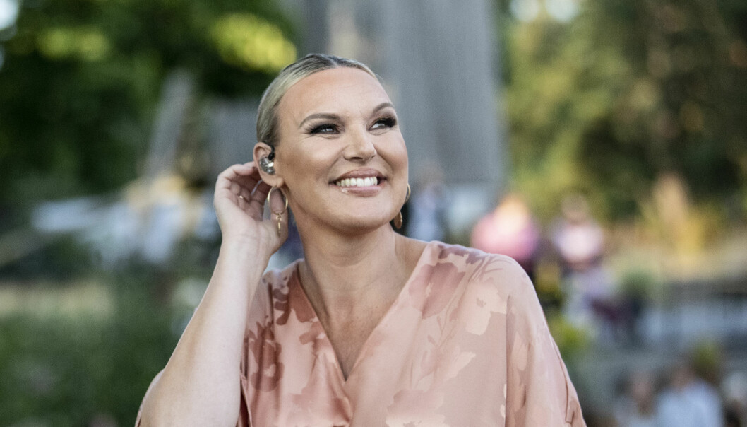 Sanna Nielsen tittar åt sidan och ler med grönska i bakgrunden.