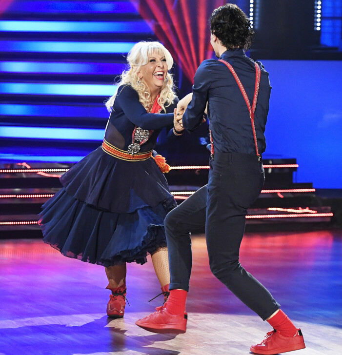 Pia Johansson och danspartnern Marc Christensen i Let’s dance 2016. Hon anknöt till sitt samiska arv genom att bugga i en samisk klänning. Bild på Pia och sin danspartner på dansgolvet i Lets Dance. De har på sig mörkblåa kläder och röda skor. Pia skrattar och de håller i varandra i en dansrörelse.
