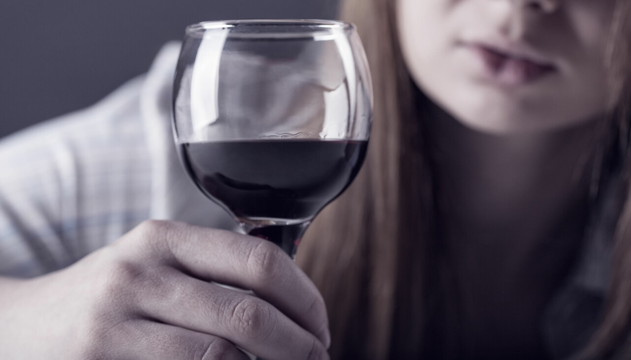 Kvinna håller i vinglas med rödvin
