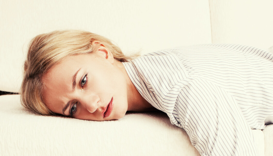 Kvinna trött och utslagen på soffan.