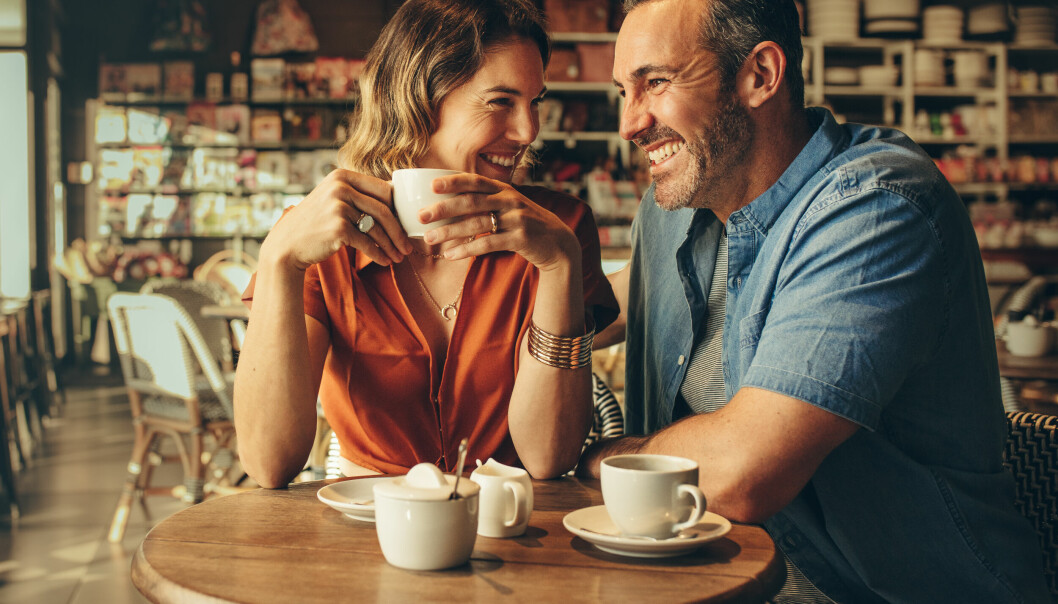En man och en kvinna sitter på ett café och fikar. De skrattar.