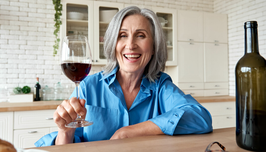 En kvinna som dricker vin vid ett bord