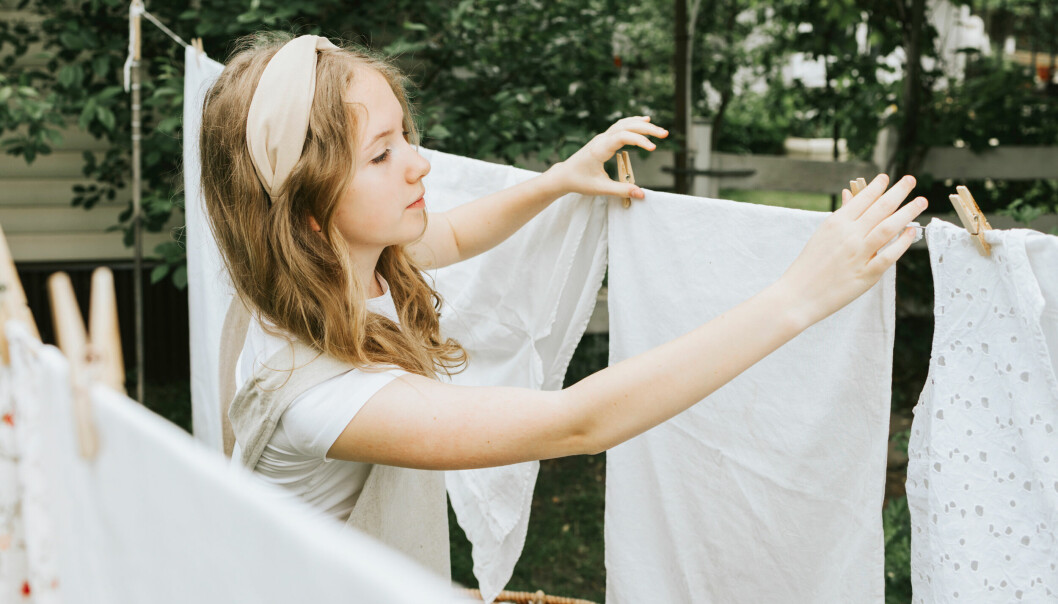 Ung kvinna som hänger tvätt på tvättlina