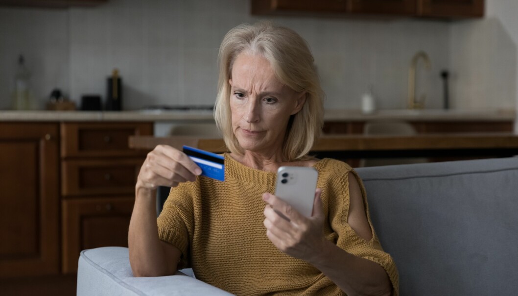 Kvinna håller i en mobiltelefon och ett bankkort.