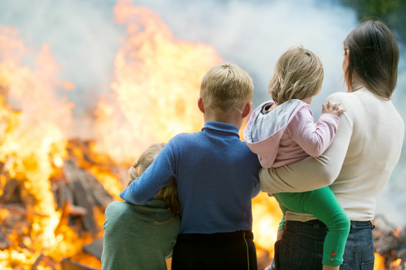 Kvinna står med två små barn vid brand.
