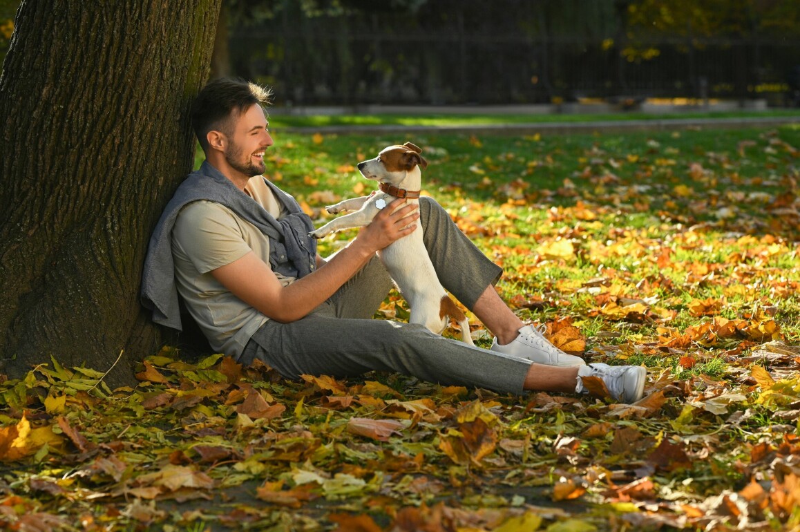 En man tillsammans med en hund i parken
