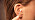 Bild på en persons öra och en hand som håller en tops mot örat.