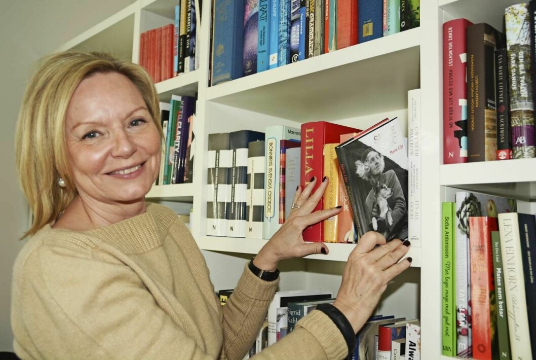 Maria Liljas släkting Sigge Stark skrev 115 romaner och mer än 500 noveller under sin livstid. Foto: Charlotta Rönn. Maria Lilja glad vid bokhyllan, plockar out den egna boken om Sigge Stark.