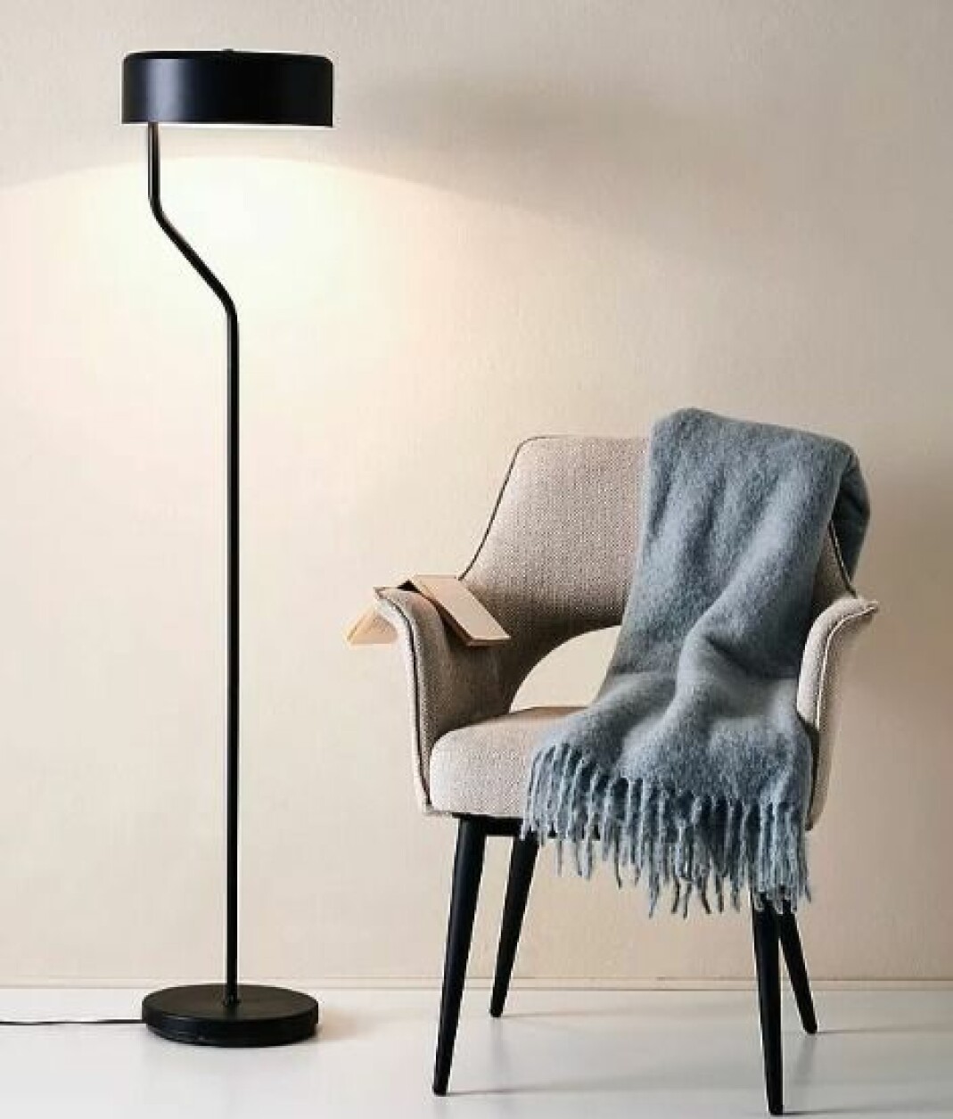 Svart golvlampa i metall, läslampa med vit insida på skärmen.