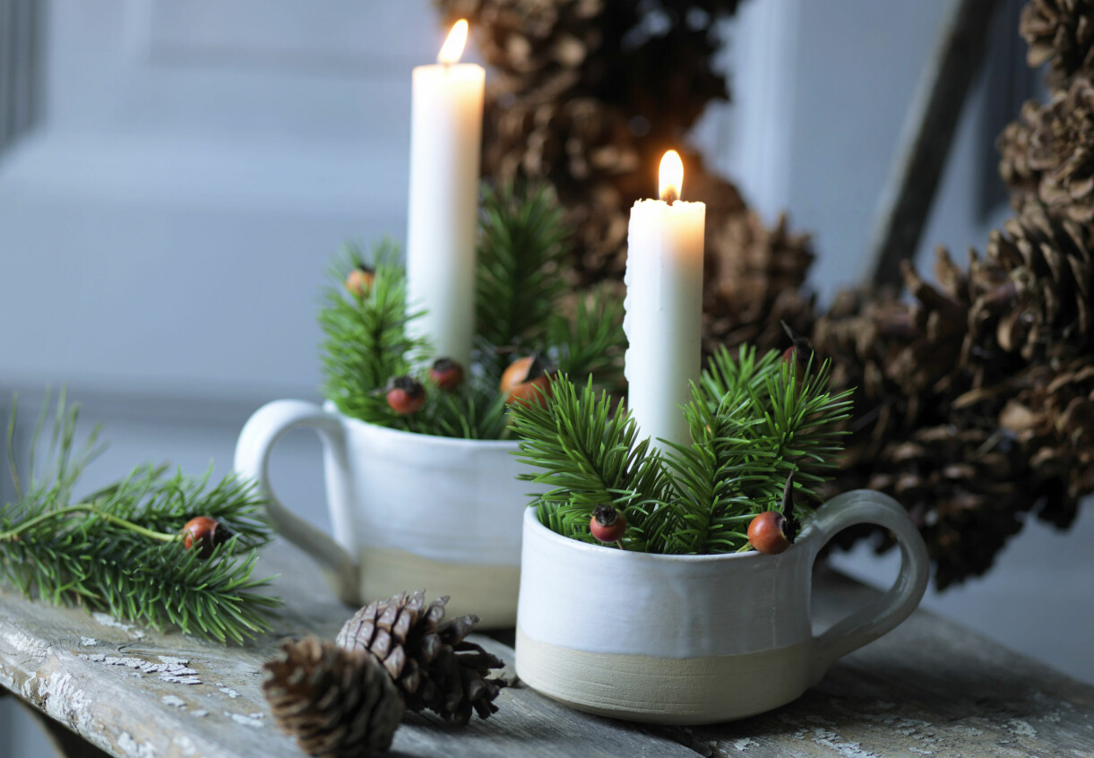 Små adventspynt med levande ljus i muggar.