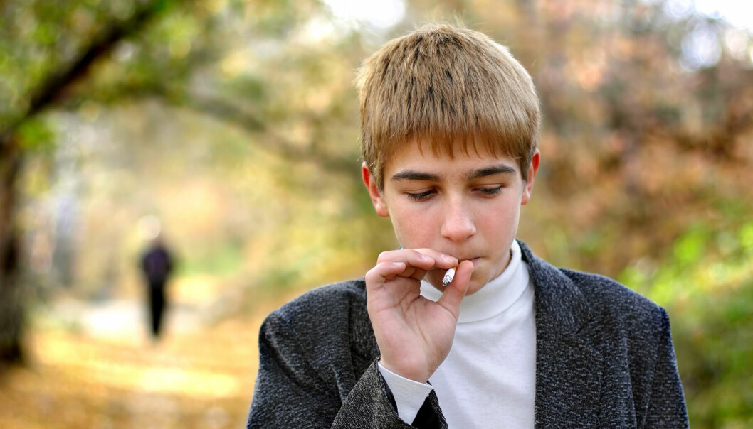Tonåring röker en cigarett.