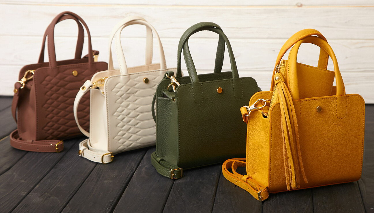 Fyra handväskor i olika färger står uppradade.