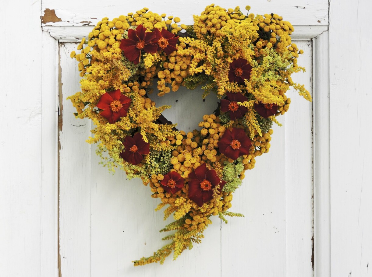 Gul och glad sensommarkrans av renfana, gullris och tagetes. Stommen är stickmassa och oasis i en hjärtform. Gul sensommarkrans med rengana, gullris och tagetes.