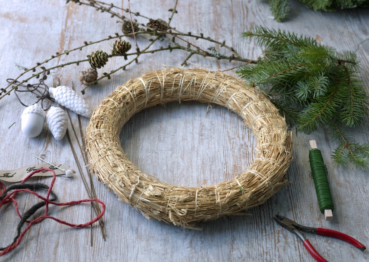 Fäst spoltråd runt halmstommen. Steg ett i att göra vår adventskrans av gran: Fäst spoltråden runt halmstommen.