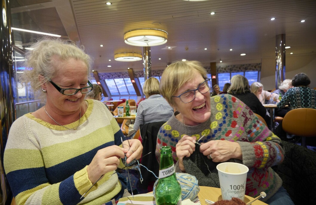 Susanne Karlsson och Berit Olehn har en trevlig stund medan de stickar varv efter varv på nya alster. Tröjorna de har på sig har de också gjort själva. Två kvinnor stickar på och skrattar ihop. I bakgrunden syns andra handarbetare, och havet genom fönstren.