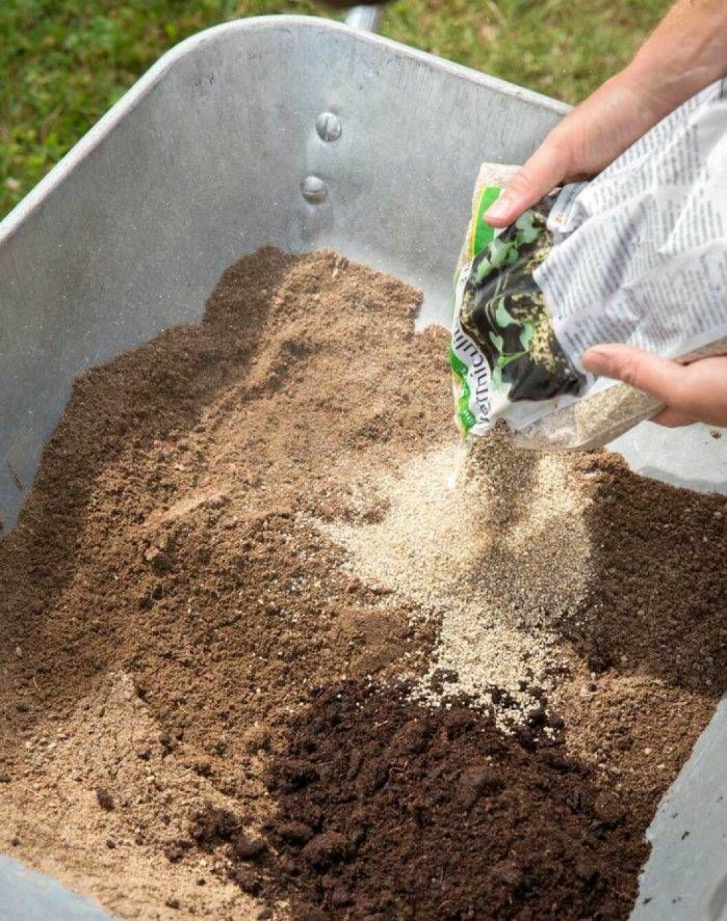 Fyller en skottkärra med sand och planteringsjord.