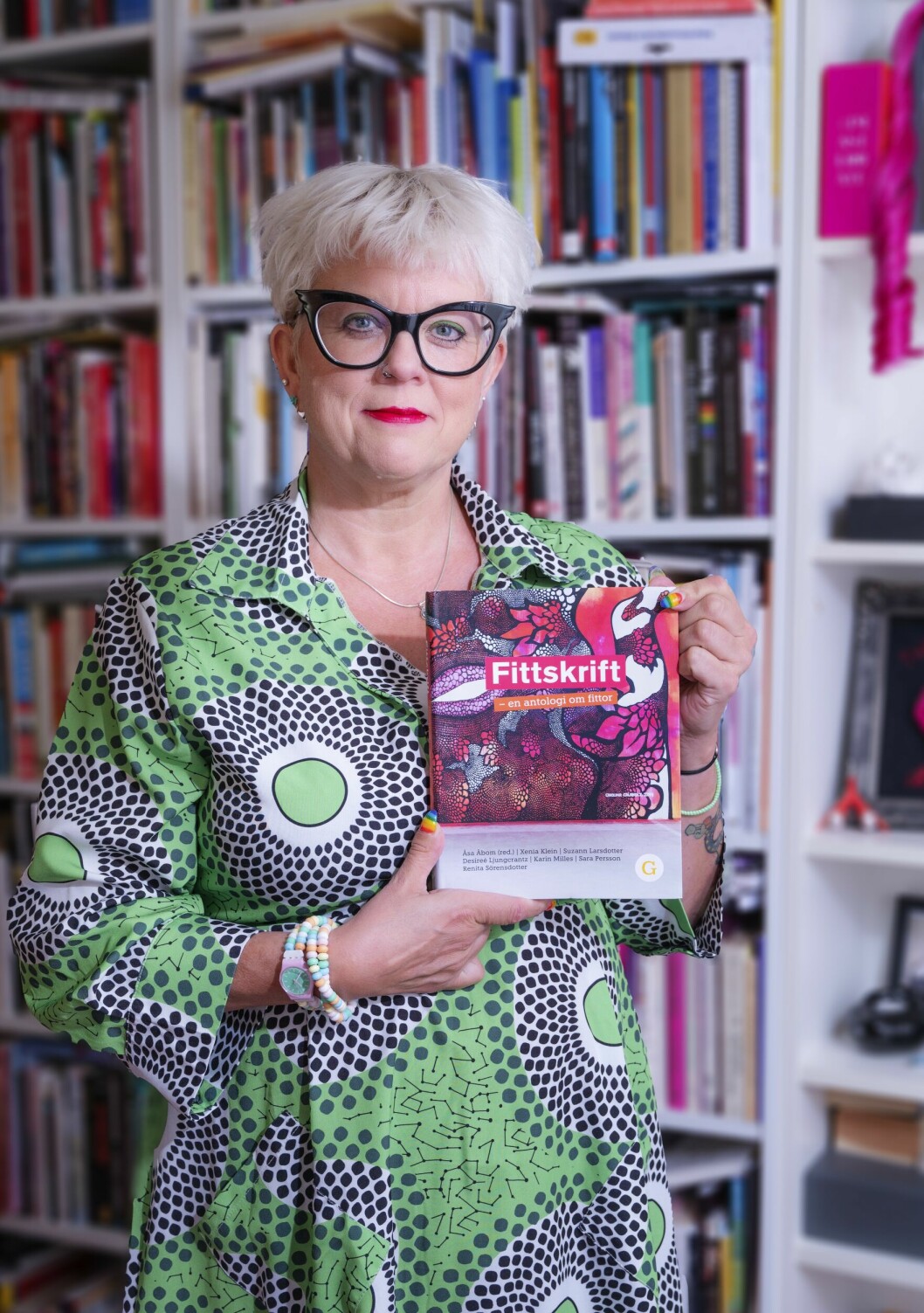 Sexologen Suzann Larsdotter håller upp boken Fittskrift, i vilken hon medverkar.