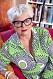 Sexologen Suzann Larsdotter - med markanta, svarta glasögonbågar, knallrött läppstift och grön-vit-svart mönstrad klänning - berättar om tiden i Livets ord och andra frikyrkoförsamlingar.