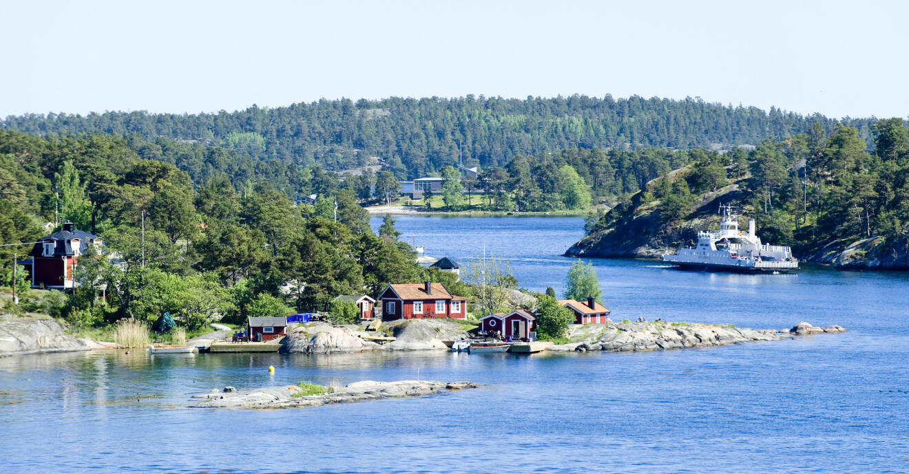 Högsommar i den svenska skärgården med båtar på vattnet och röda stugor på land.