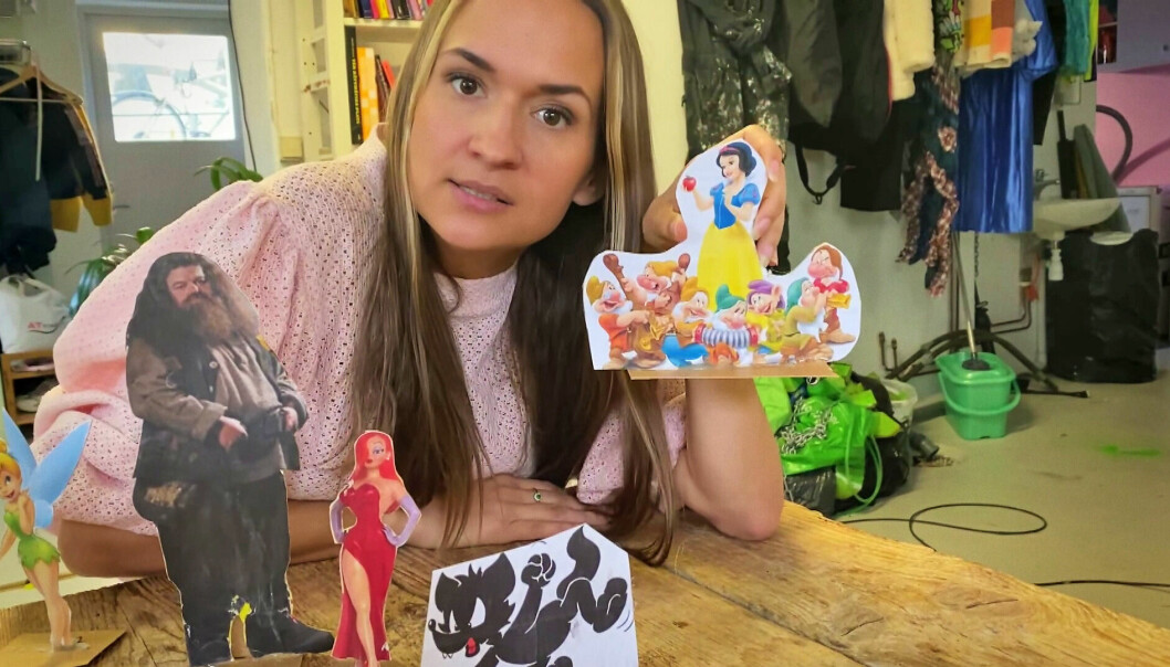 Bianca Kronlöf håller upp en bild av Snövit och de sju dvärgarna och tittar in i kameran under inspelningen av tv-serien Ta det som en man.
