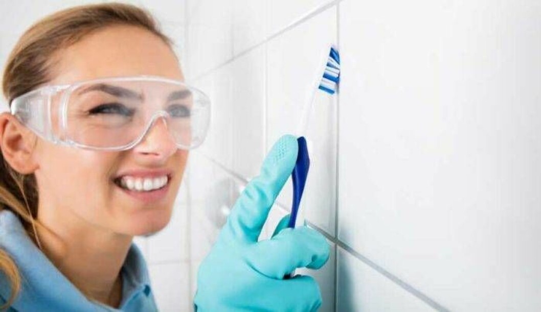Kvinna som rengör badrummet med en tandborste.