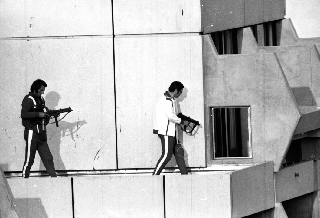 Poliser i idrottskläder och med automatvapen uppe på en byggnad.