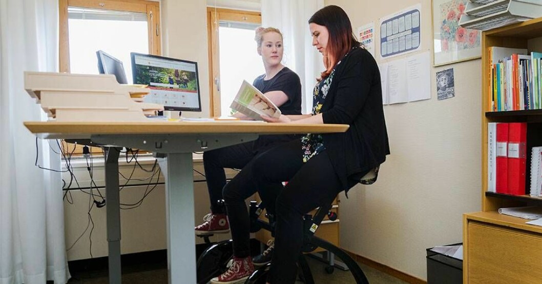 Viktoria Elmbro och Emma Wiss mår bra av att kombinera stillasittande arbete på kontor med att cykla. Foto: Kristina Wirén Viktoria Elmbro och Emma Wiss på kontorscyklar.