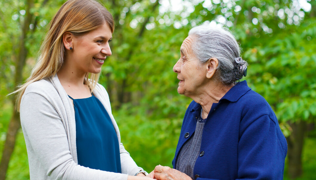 Kvinna håller en äldre dement kvinna i handen