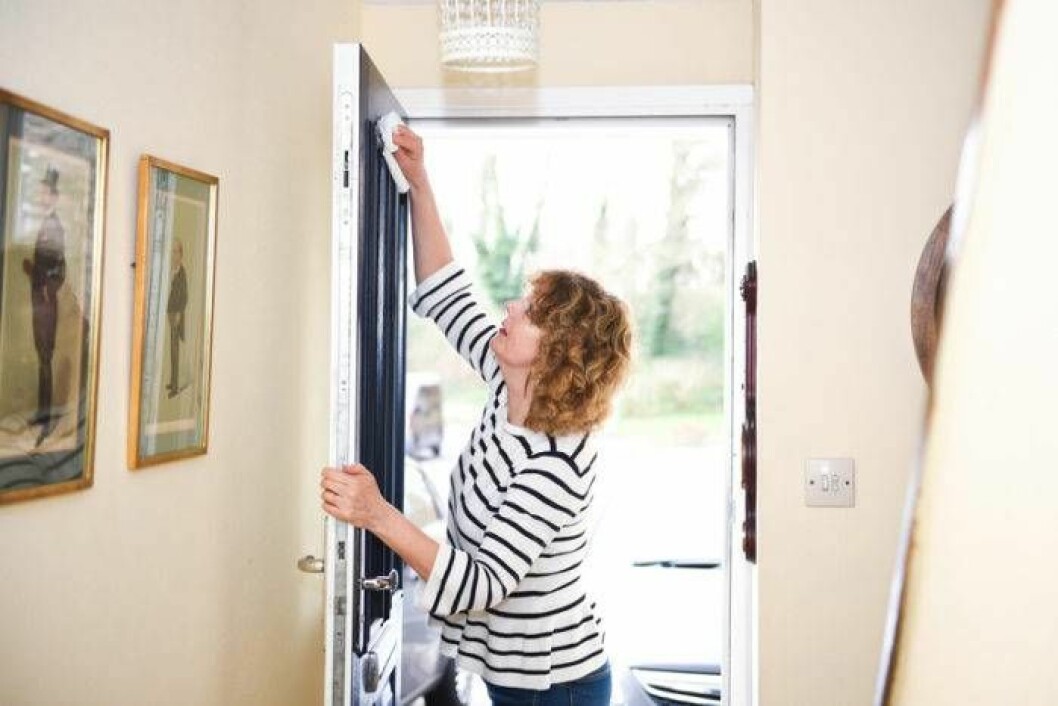 Glöm inte bort att torka av dörrar och lister. Foto: Shutterstock/IBL Kvinna torkar av dörr.