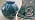 Till vänster klotformad vas i blågröna nyanser med silverdekor. Till höger Kåges signatur för Gustavsberg.