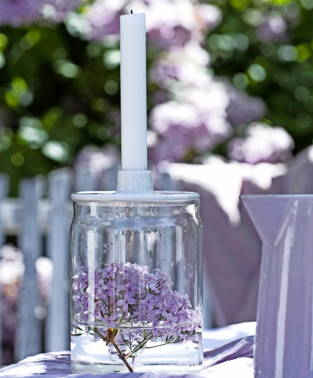Vas och ljusstake med syrenblommor i.