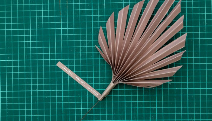 La carta piegata viene incollata attorno al bastoncino del fiore