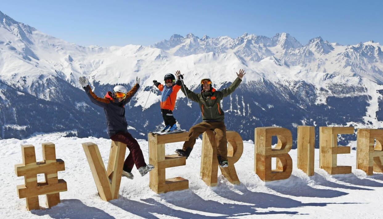 Under vinterhalvåret bor Johanna, Anders och Walter i Verbier, där Johanna arbetar som skidlärare och Anders som extreme ski coach. Foto: Privat Johanna, Anders och Walter sitter på stora träbokstäver som formar namnet Verbier i en skidbacke.