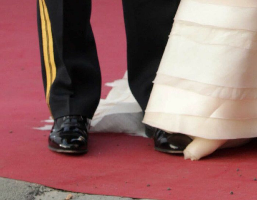 Prinsen parkerad på chiffongen. Närbild på när Carl Philip trampar på kronprinsessan Victorias släp.