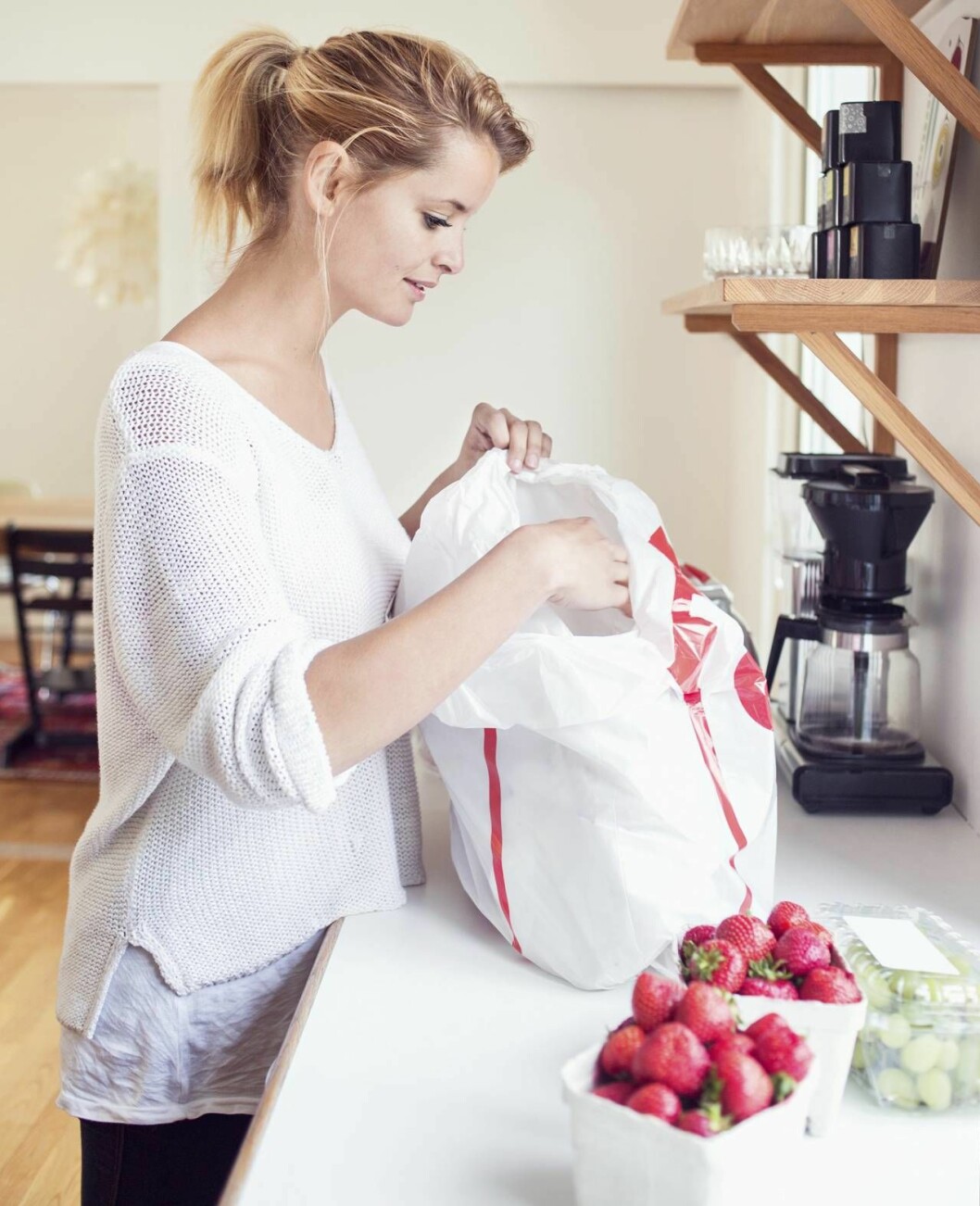 Kvinna packar upp varor ur en plastpåse