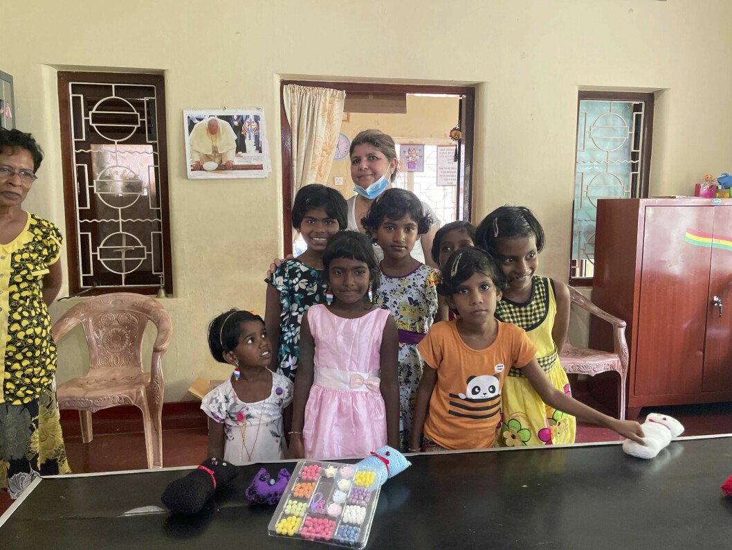 Denna höst kom Yolanda återigen iväg på en resa till Sri Lanka. Här hos barnen på ett barnhem som fått del av gåvorna. Sju flickor på ett barnhem, med pysselsaker framför sig på bordet. I bakgrunden ses Yolanda med munskydd, som dragits ned under hakan.