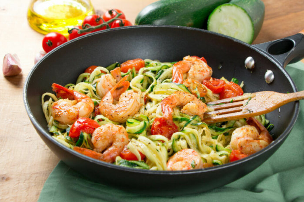 Zucchini-spaghetti tillsammans med räkor och tomater. Bild: Shutterstock/IBL Zucchini spaghetti i stekpanna med tomat och räkor.